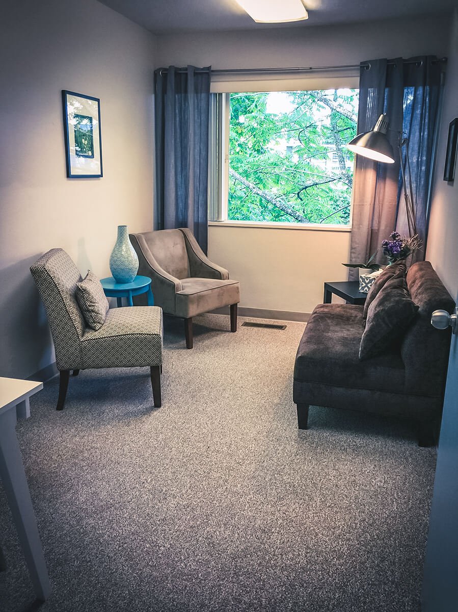 a room with two chairs and a couch looking out onto a wooded area